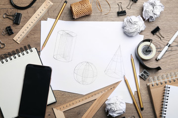Flat lay composition with drawing of geometry shapes on wooden table. Designer's workplace