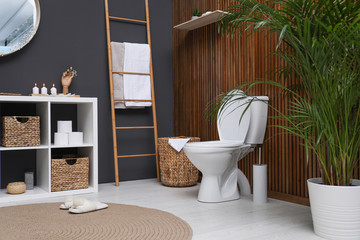 Elegant modern bathroom with toilet bowl near wooden wall