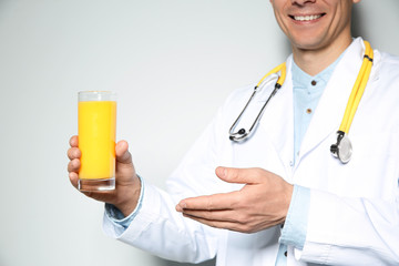 Nutritionist with glass of juice on light grey background, closeup