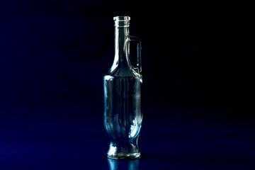 Obraz na płótnie Canvas Empty glass bottle with a handle on a deep blue background.
