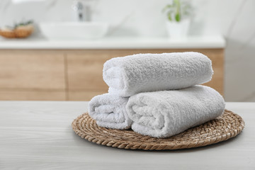 Fototapeta na wymiar Rolled fresh towels on white table in bathroom