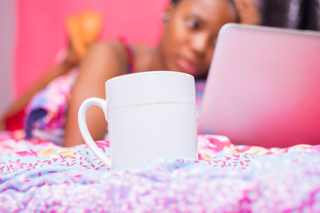 pretty african lady at home alone in her bedroom, watching a movie on her laptop pc looking scared...
