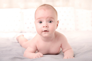 Happy young baby lying on tummy on a white background.