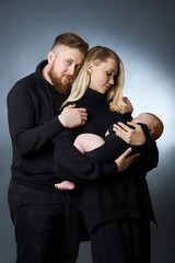 Man and a woman hold a baby in their arms. Portrait of a married couple after the birth of a child. Young family