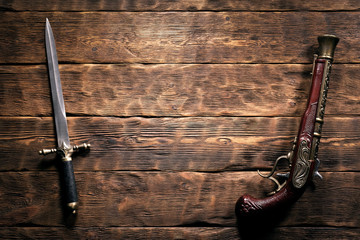 Ancient weapon on brown wooden table background with copy space. Pirate concept.