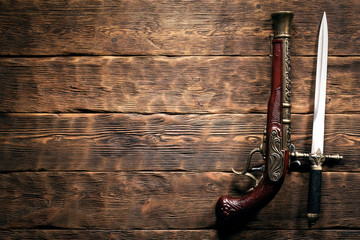 Ancient weapon on brown wooden table background with copy space. Pirate concept.