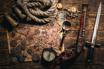 Pirate treasure map on brown wooden table flat lay background.