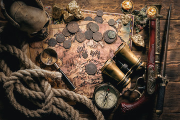 Pirate treasure map on brown wooden table flat lay background.