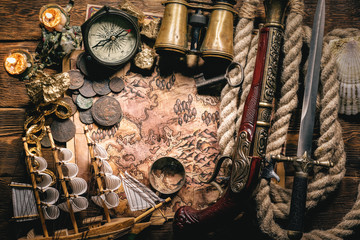Pirate treasure map on brown wooden table flat lay background.