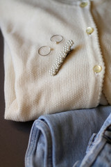 Fototapeta na wymiar Vintage white cardigan, light wash mom jeans, floral hair beret and rings. Selective focus.