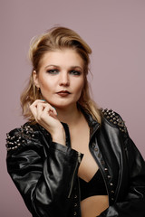 Woman blonde in leather jacket looking at camera isolated in studio