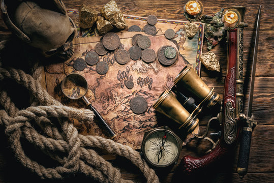 Pirate treasure map on brown wooden table flat lay background.