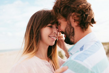 Young couple in love outdoor.Stunning sensual outdoor portrait of young stylish fashion couple posing in summer  on the ocean beach.Close up portrait of smiling young couple having fun outdoors.