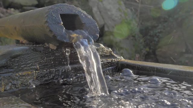 Primer plano y en c&aacute;mara lenta de fuente de madera y agua salpicando