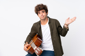 Young caucasian man with guitar over isolated white background having doubts with confuse face expression