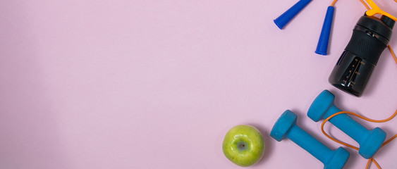 Fitness concept banner with dumbbells, jump ropes and measuring tape on a pink background.