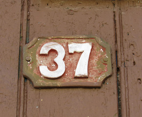 Vintage grunge square metal rusty plate of number of street address with number. Close up, brand.