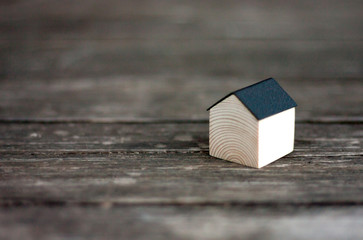 Miniature wooden house with black metal roof on rustic wood background