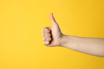 Female thumbs up on yellow background, space for text - obrazy, fototapety, plakaty