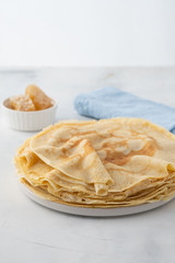 Crepes, thin pancakes with honey on a white plate. Marble background. Close up.