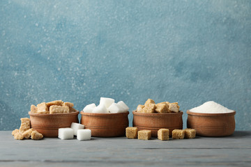 Bowls with different sugar on wooden background, space for text