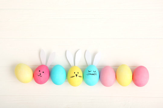 Easter eggs with cute faces and ears on a colored background.