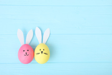 Easter eggs with cute faces and ears on a colored background.