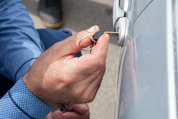 The car door has jammed. A man is trying to open the door with his key. Hands hold the key and...