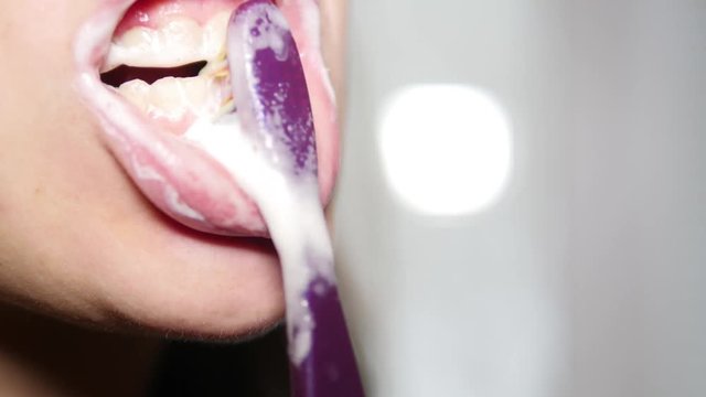 A woman is brushing her teeth with an electric brush. Healthy teeth, oral hygiene