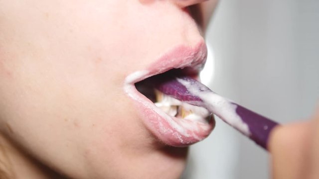 A woman is brushing her teeth with an electric brush. Healthy teeth, oral hygiene