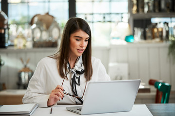 Attractive businesswoman sitting in cafe and using laptop.