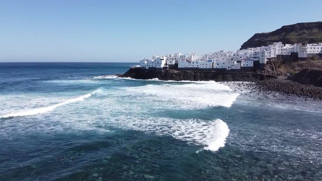 Old fisherman's town on the coast line, filmed with drone, blue waves. Spain, Gran Canaria