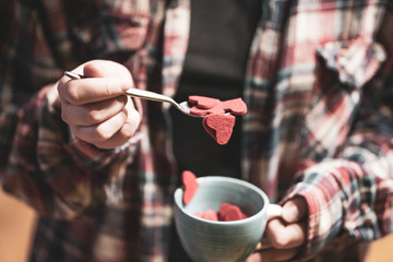 Woman holding cup full of red heart shape figures. Valentine's day concept. Selective focus.