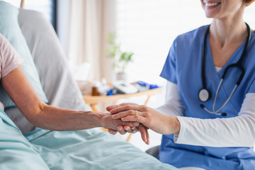 Unrecognizable female doctor examining patient in bed in hospital.