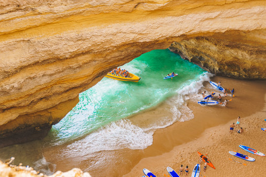 Benagil cave in Portugal, Carvoeiro Algarve, Lagos. Tourists swimming on paddle boards for SUP, kayak, motor boats to Praia de Benagil. Top view. Blurred people enjoy tourist boat tour