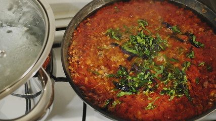 Top view: Making bolognese sauce in a pan, adding basil and parsley. Italian food concept