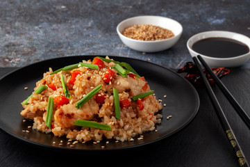 Tori chahan fried Japanese rice with vegetables and chicken in soy sauce in a black plate on a serving board