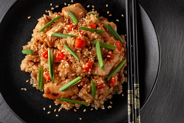 Tori chahan fried Japanese rice with vegetables and chicken in soy sauce in a black plate on a serving board