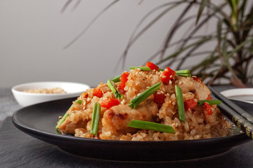 Tori chahan fried Japanese rice with vegetables and chicken in soy sauce in a black plate on a serving board