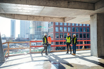 Group of engineers standing on construction site, talking.