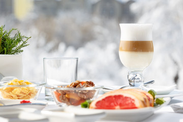 Latte coffee on the terrace in front of the restaurant against the snow.