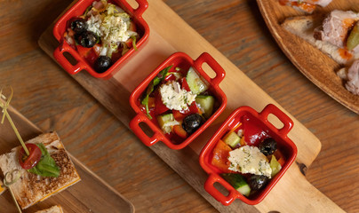 Organic caesar salad in red bowl with caesar dressing. Wooden table, luxury catering.