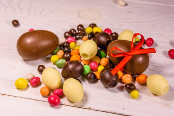 Chocolate easter eggs and multicolored candies on wooden table