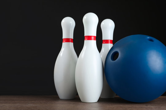 Blue bowling ball and pins on wooden table