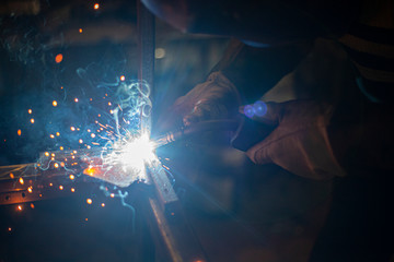 Fototapeta na wymiar A welder is cooking metal in the dark. Great glow. Creating a design. Work in the workshop.