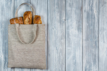 Top view of Bread in a Reusable zero waste textile bag on the white wooden background. With copy space.