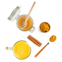 Fototapeta na wymiar Top view of a cup of golden milk with turmeric and cinnamon and wooden spoon and honey isolated on white background
