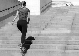 Sporty young girl in a top and leggings jogging ot the stairs. Pretty woman sporting. Concept of...