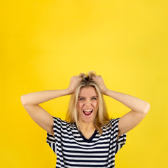 Fototapeta premium Woman in surprise joy grabbed her hair. Blonde girl surprised and shocked looks on you and screaming with delight. Expressive facial expressions emotions of fun and pleasure