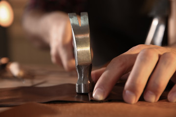 Man working with piece of leather at table, closeup